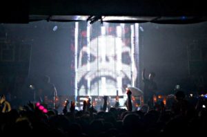 LED Cage live on stage with Camo & Krooked at a Hospitality event. Showing image of Skeletor.